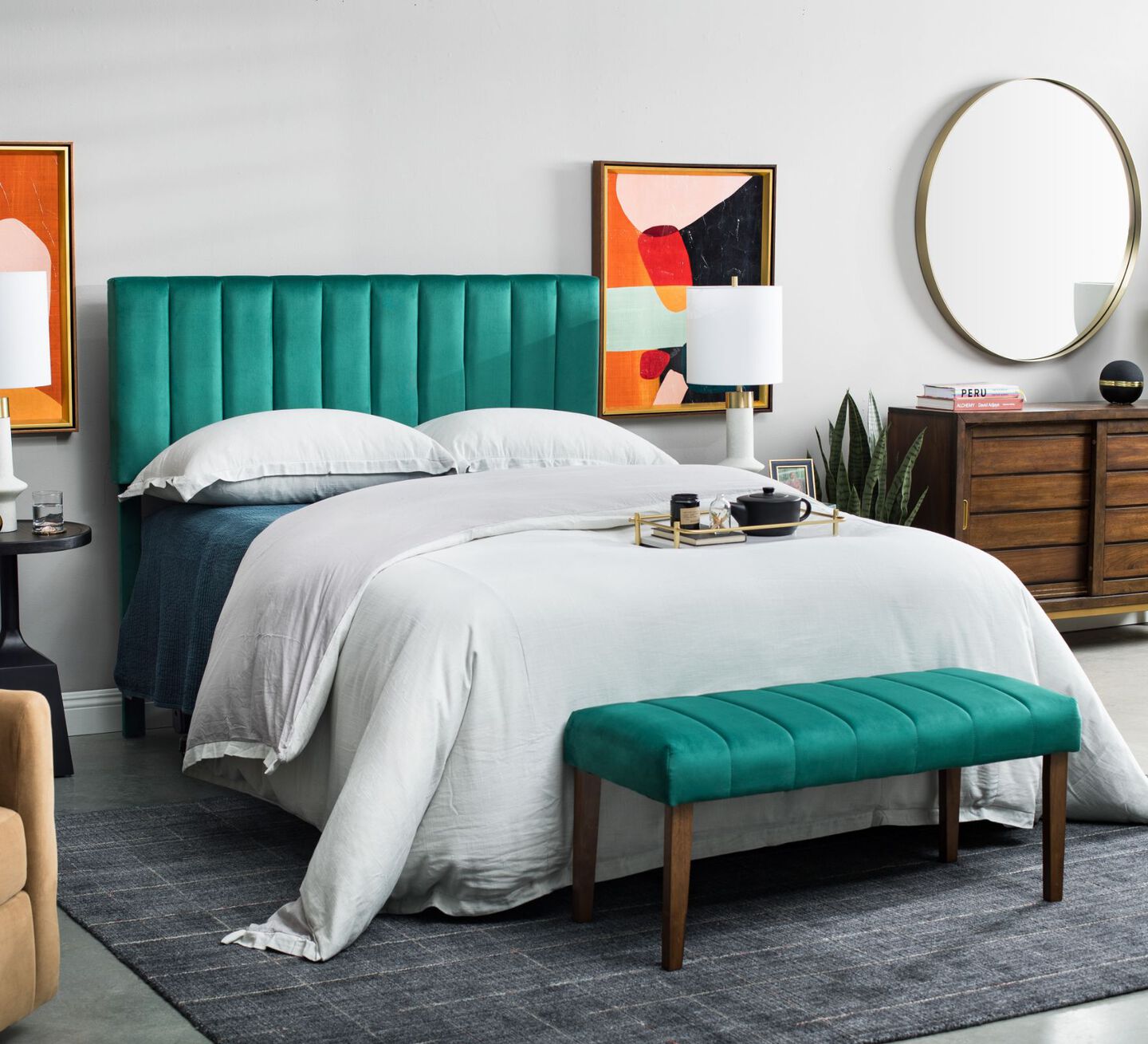 Bed with green velvet headboard and bench and white bedding and pillows