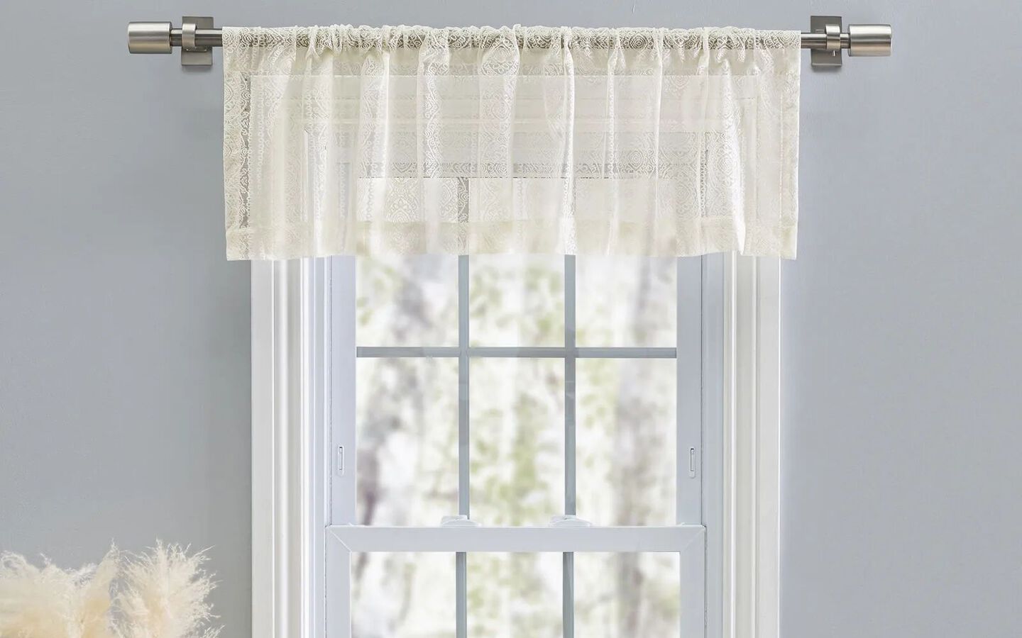 Close-up image of white window panel with short lace curtains