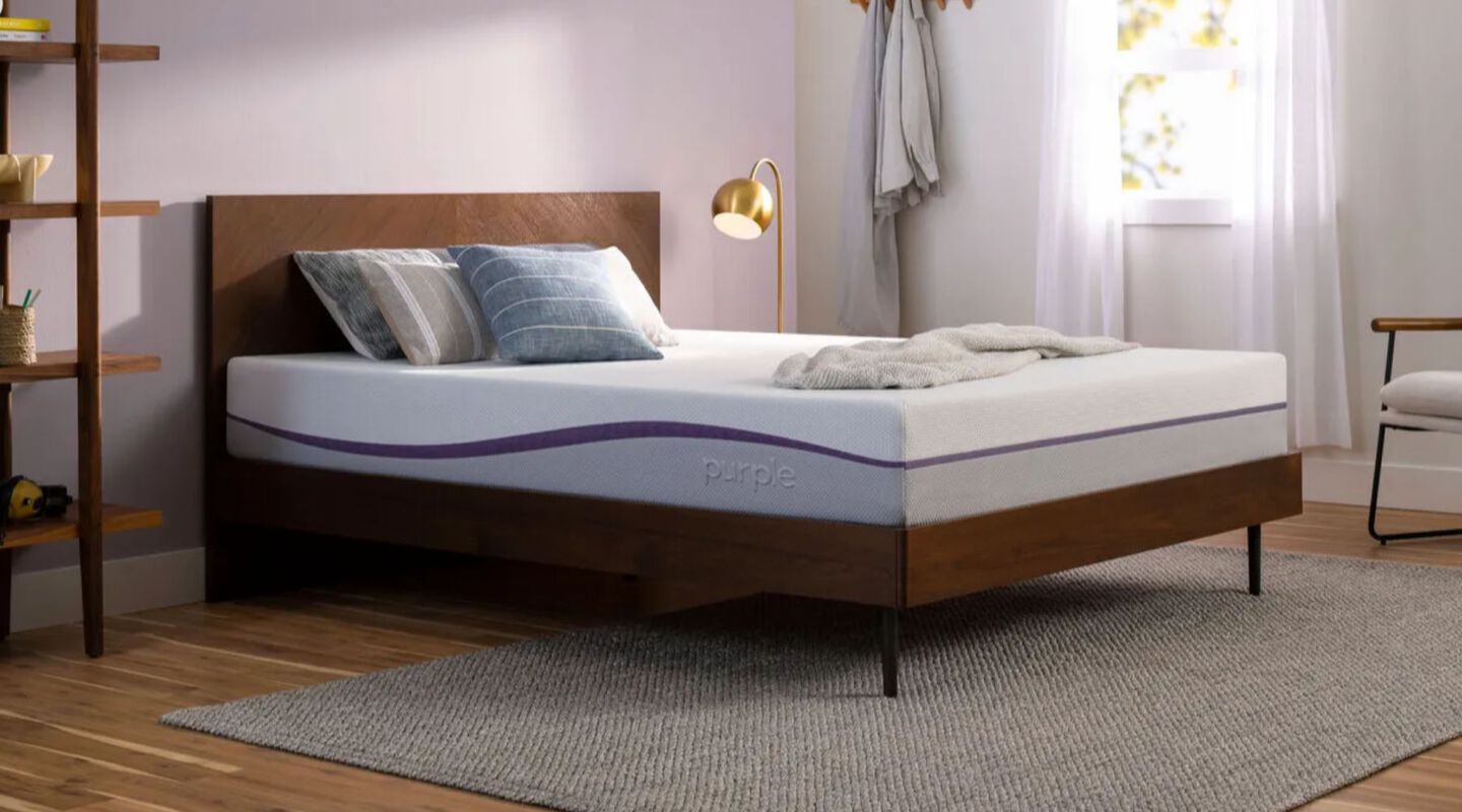 Purple mattress on top of a dark brown base in a bedroom