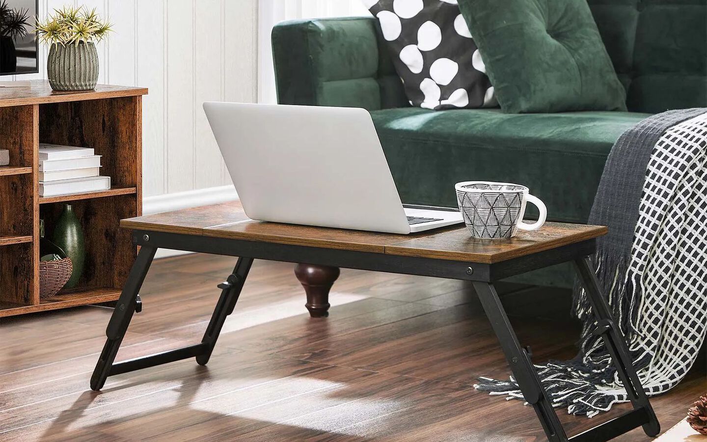 Living room with wooden laptop stand sitting in front of a green velvet couch