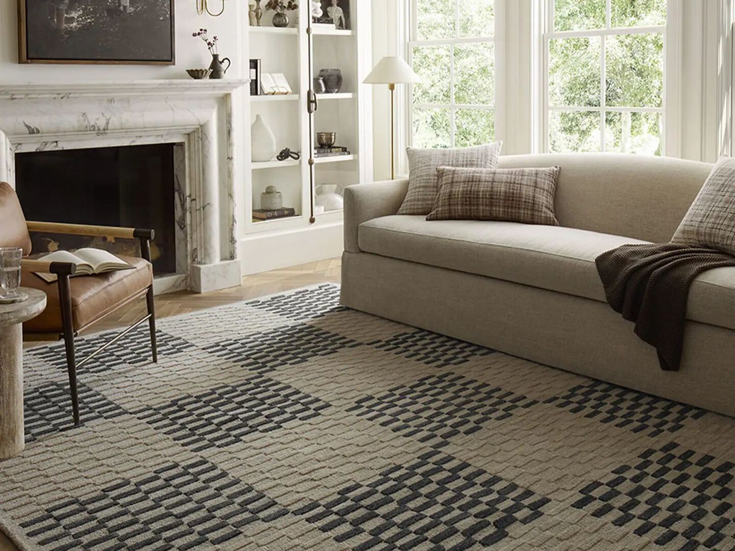 Living room with beige couch, fire place, and a navy and white checkered rug