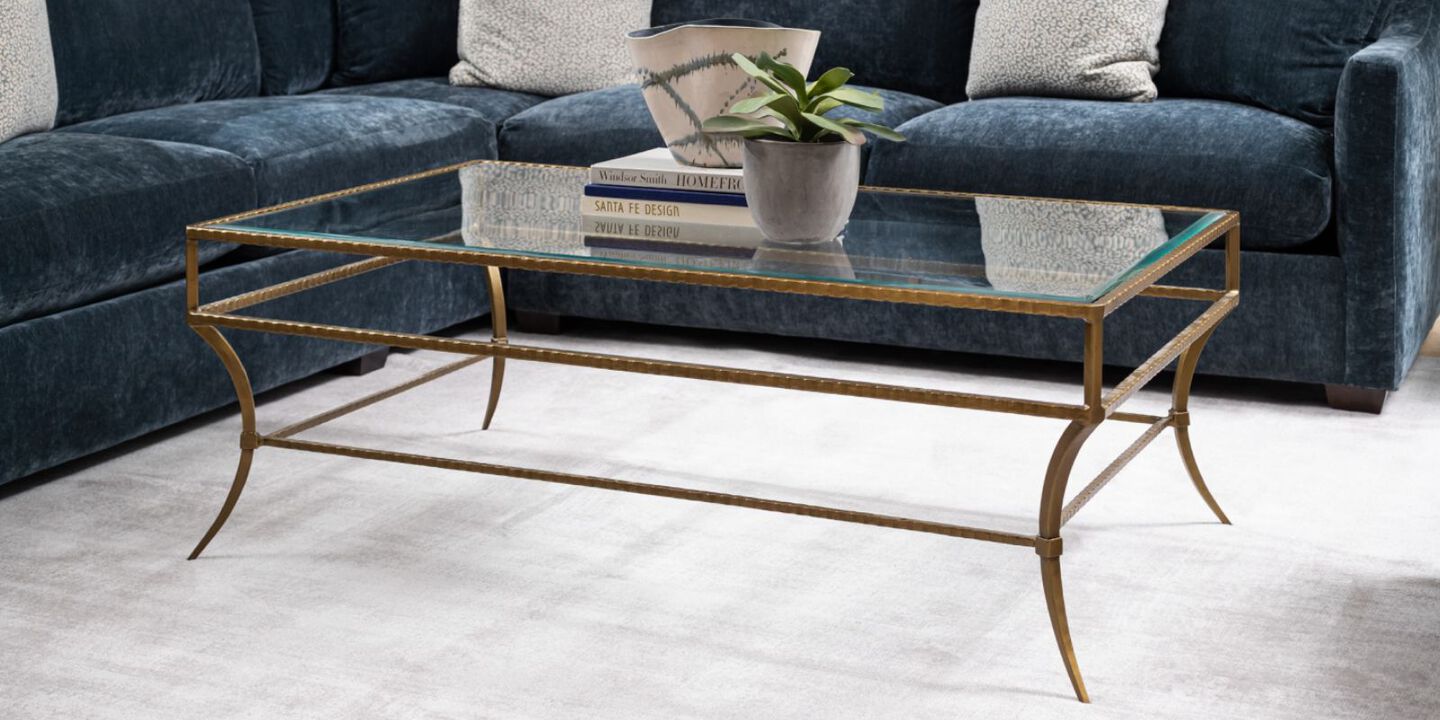 glass coffee table with gold edges sitting on a light grey rug