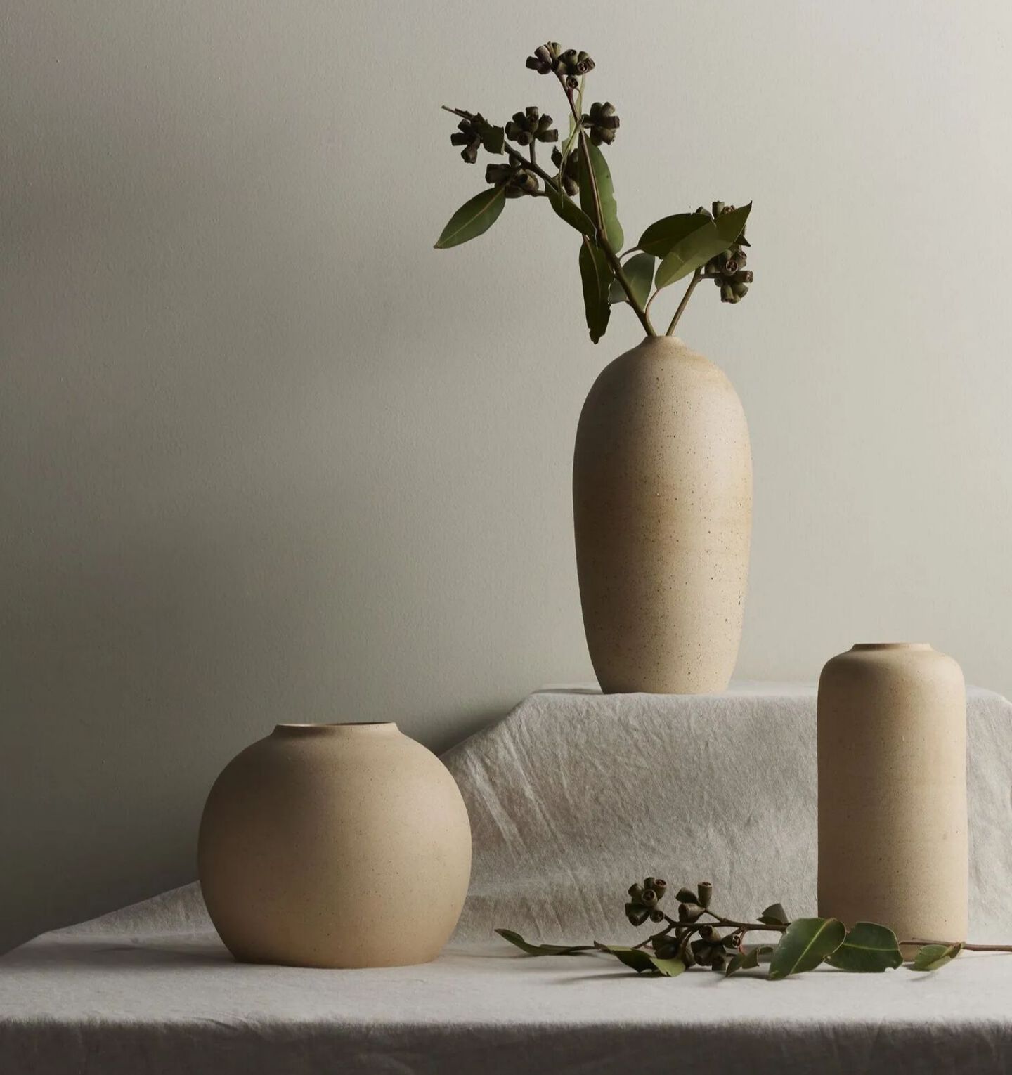 Grey table with three beige vases sitting on top