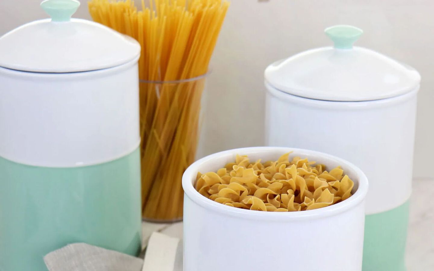 Light mint and white containers filled with uncooked pasta