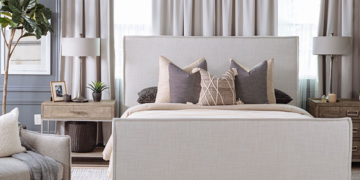 bedroom with two nightstands and a bed with a light grey upholstered bedframe and beige bedding