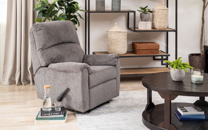 living room with grey recliner, light-grey rug, and dark brown coffee table