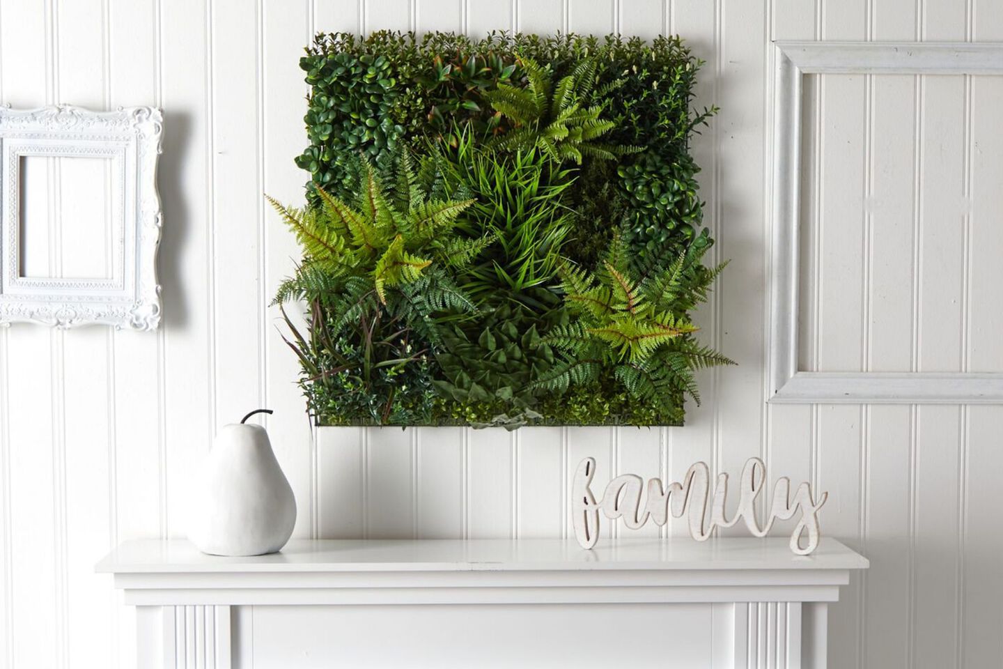 Canvas covered in green faux plants hanging above a white mantel