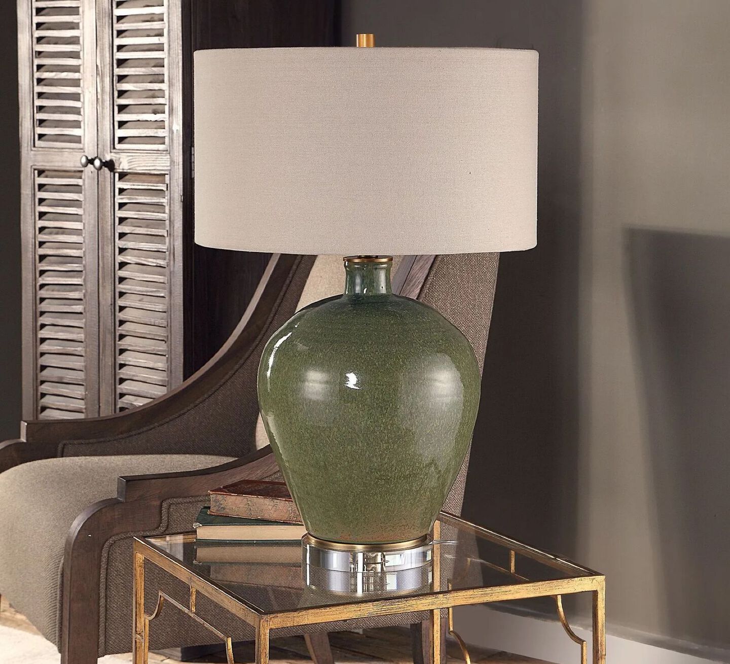 Green and ivory lamp sitting on a gold framed glass table