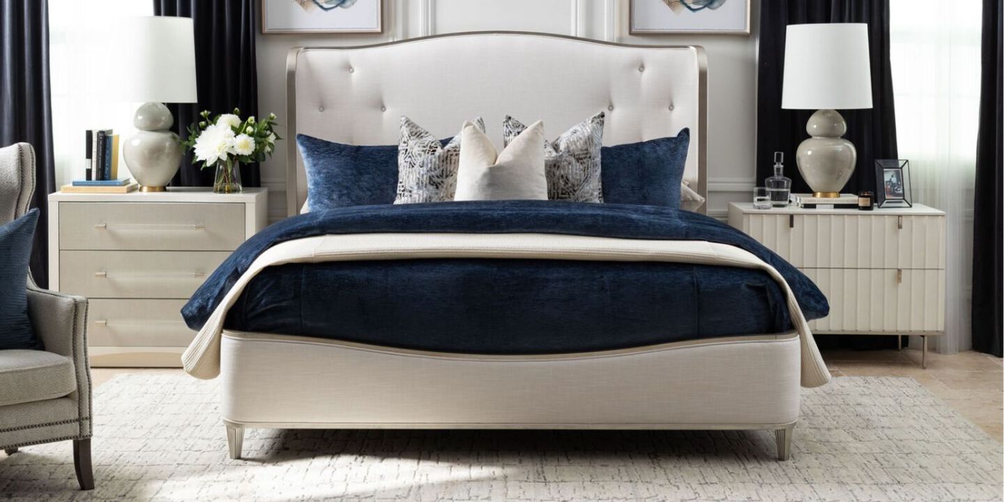 bed with navy comforter and pillows and white headboard surrounding by two white nightstands