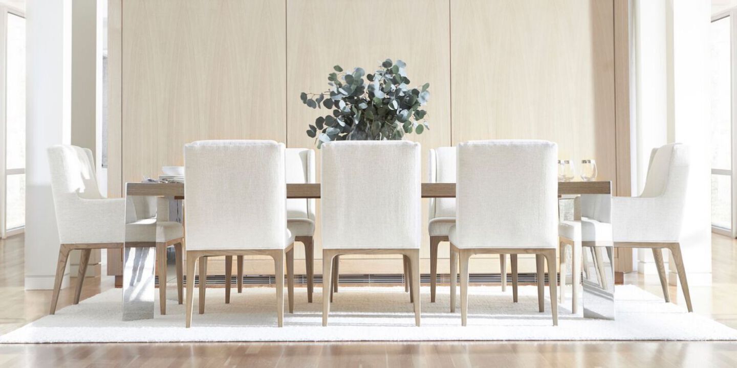 light wooden dining table surrounded by eight white and light wood dining chairs