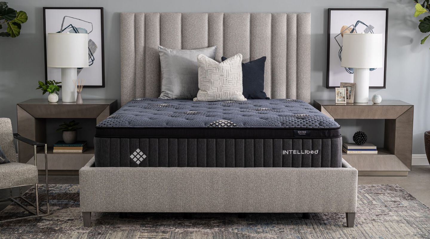 Navy blue Intellibed mattress on top of a grey baseboard with two nightstands on either side