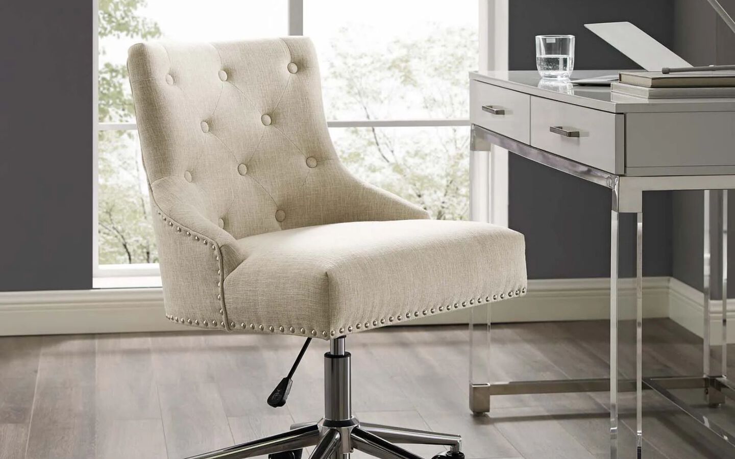 White upholstered swivel chair in front of white desk with clear glass legs