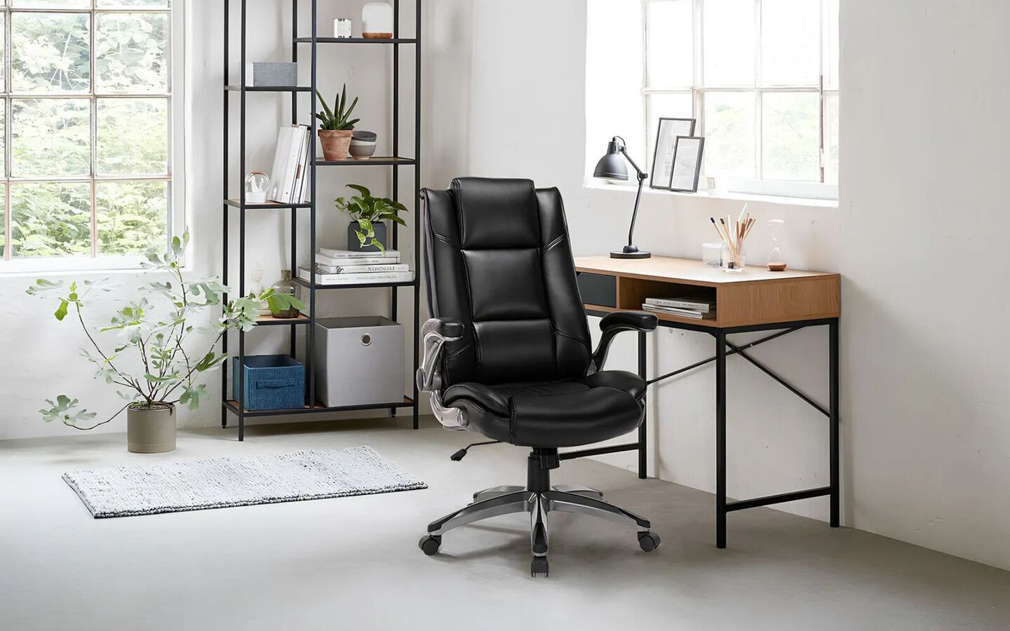 Office space with black tier shelf, brown and black desk, and a black swivel chair