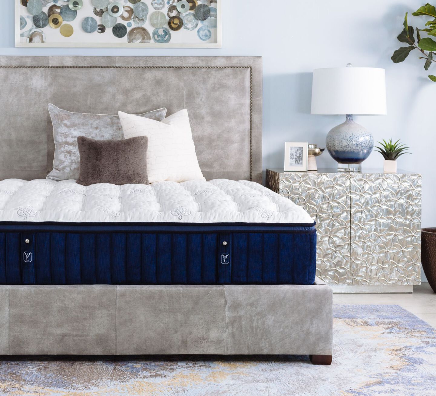 Navy blue and white William & Lawrence mattress next to a silver nightstand with a lamp