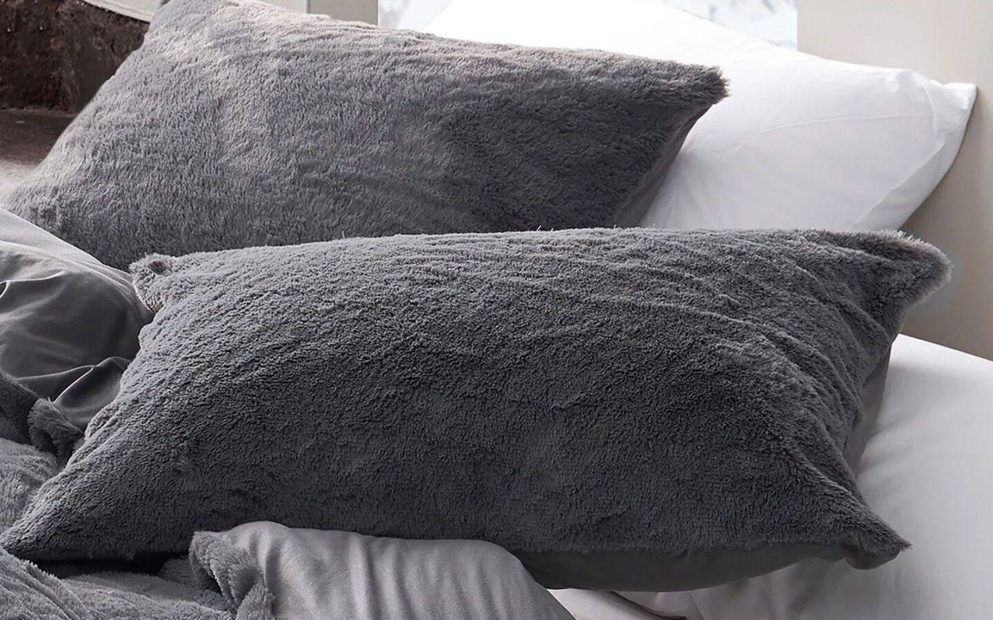 Closeup image of grey plush pillow shams on top of bed