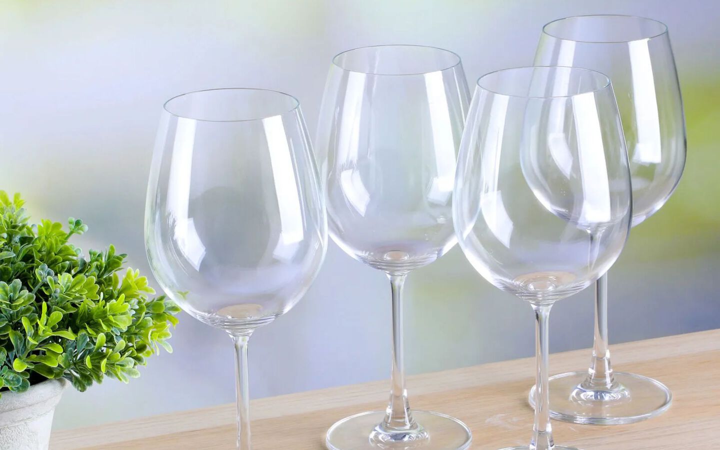 Four clear wine glasses sitting on the edge of a table