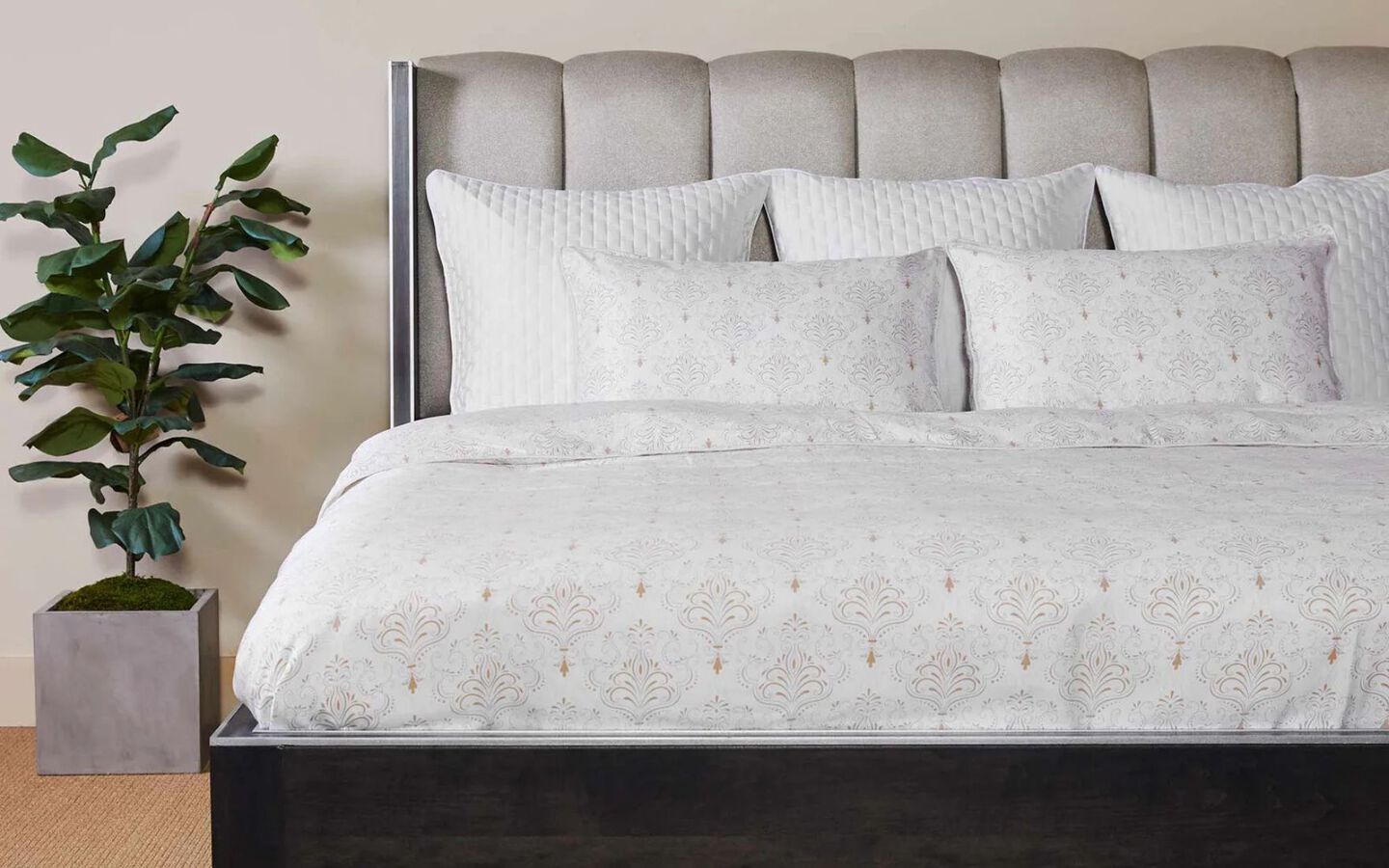 Bed with upholstered bedframe and white patterned comforter and pillows