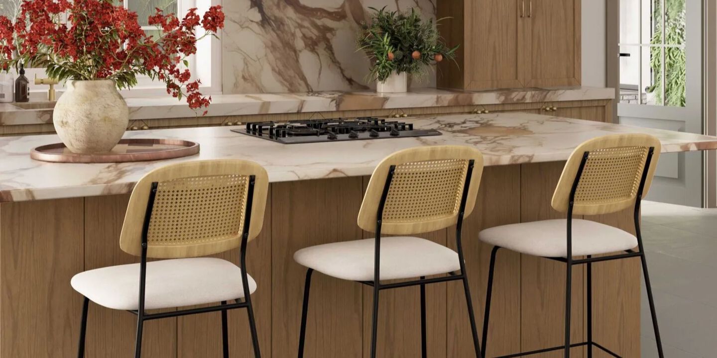 Kitchen with marbled counter top and three white barstools in front