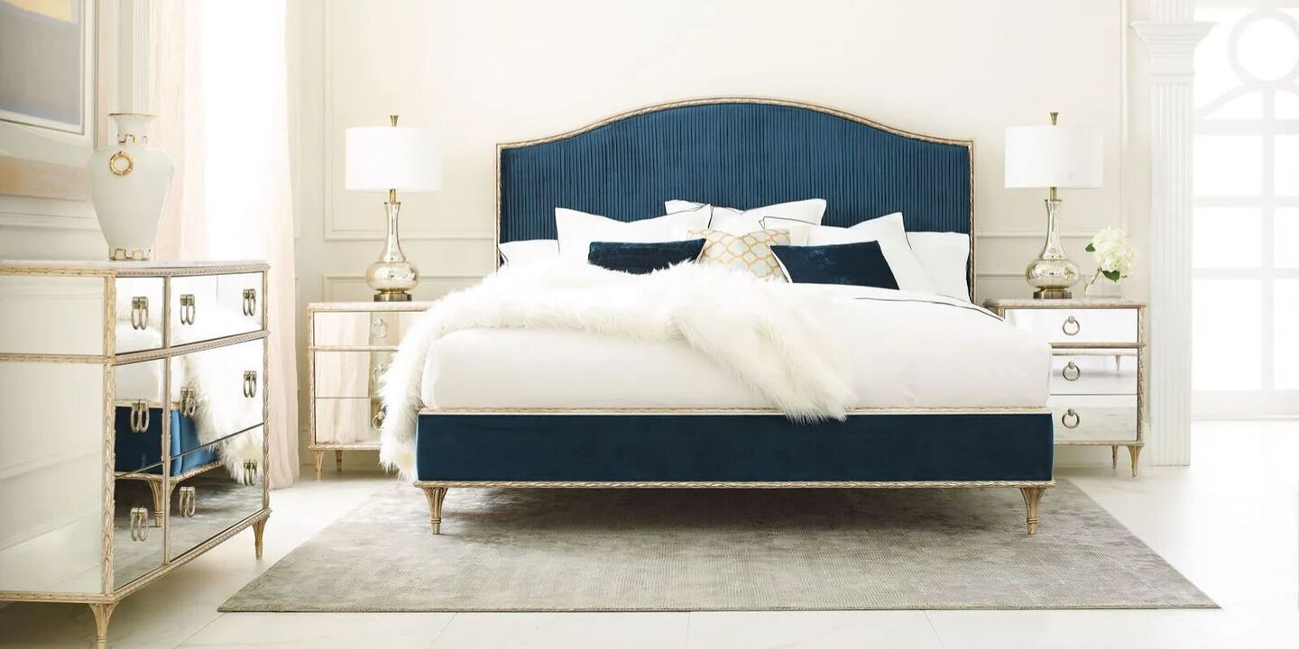 bedroom with silver mirrored furniture and a white and navy blue bed