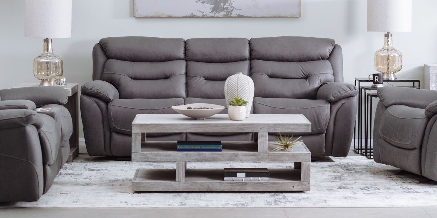 living room with light grey coffee table and a dark grey couch and two recliners