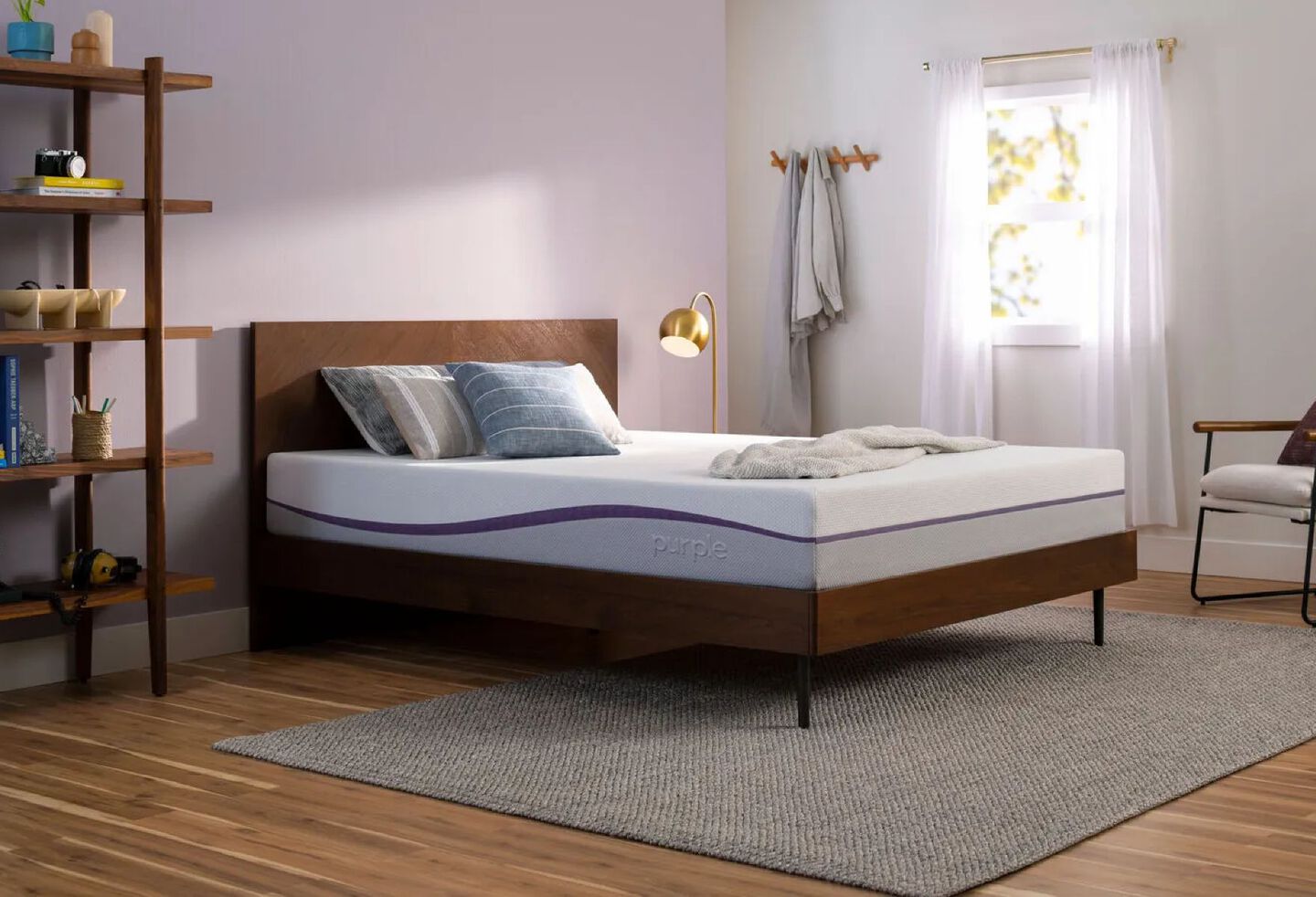 Purple mattress sitting atop a wooden bedframe in a bedroom