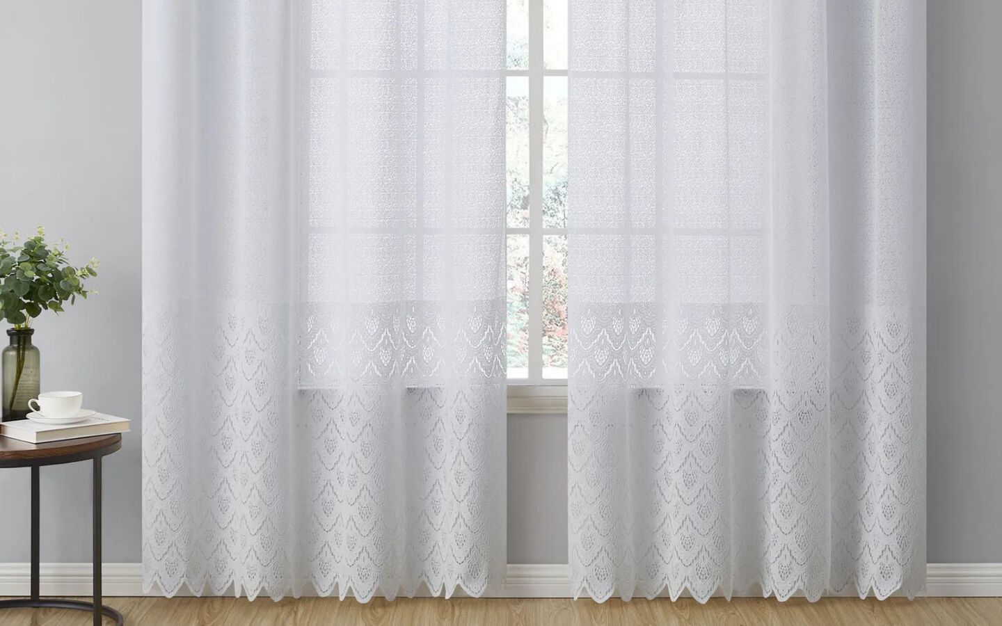 Window with white pain framed by long, white lace curtains