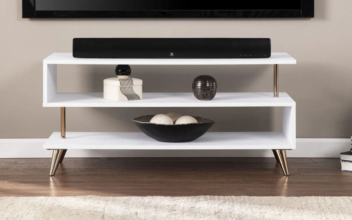 White geometric TV stand with bowl and small objects on the shelves