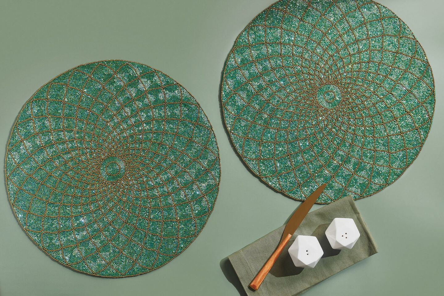 Two green beaded placemats on a muted green surface