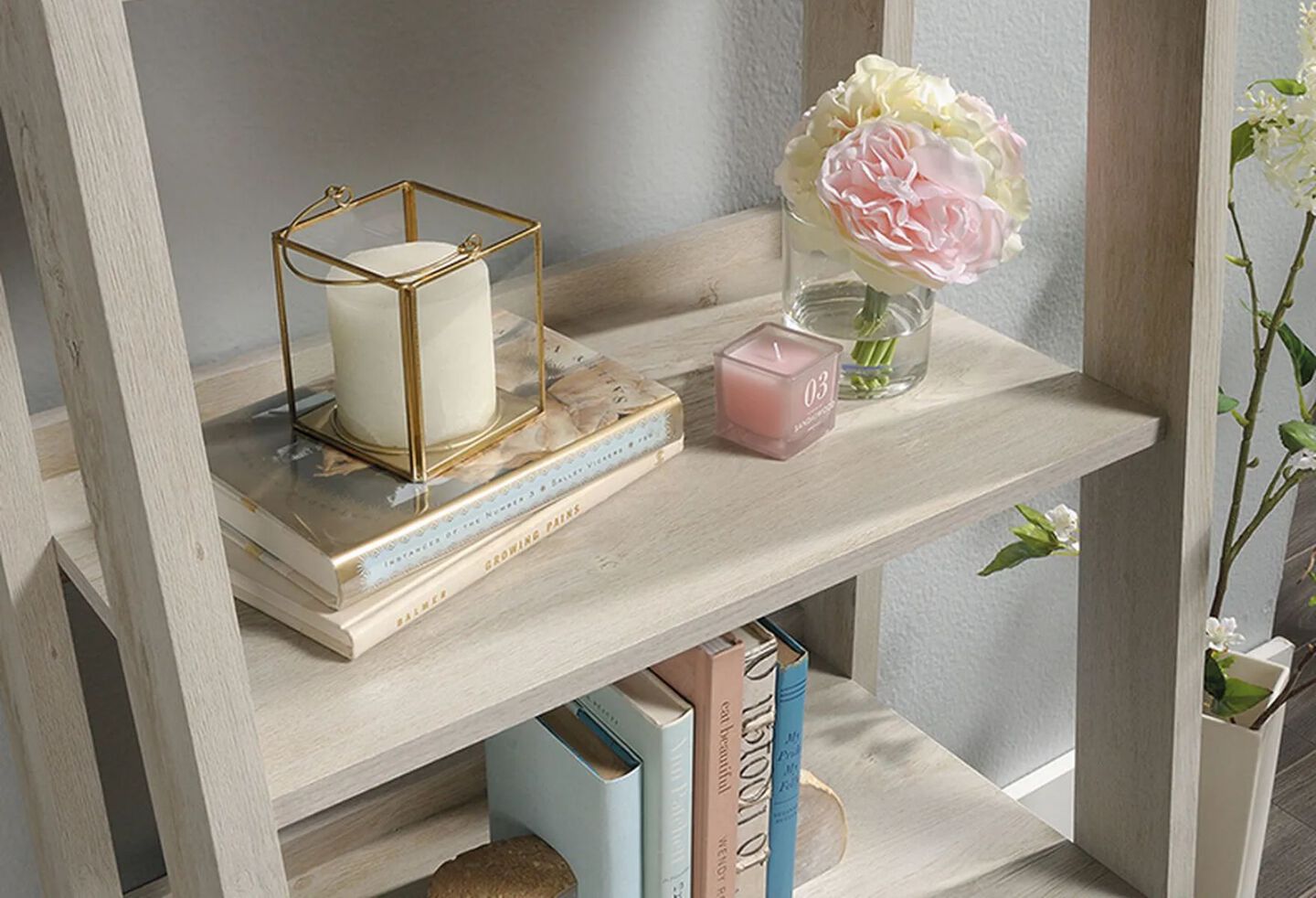 Light wooden bookshelf with books, a vase, and two candles on the shelves